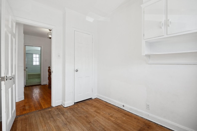 interior space with crown molding, hardwood / wood-style flooring, and baseboards