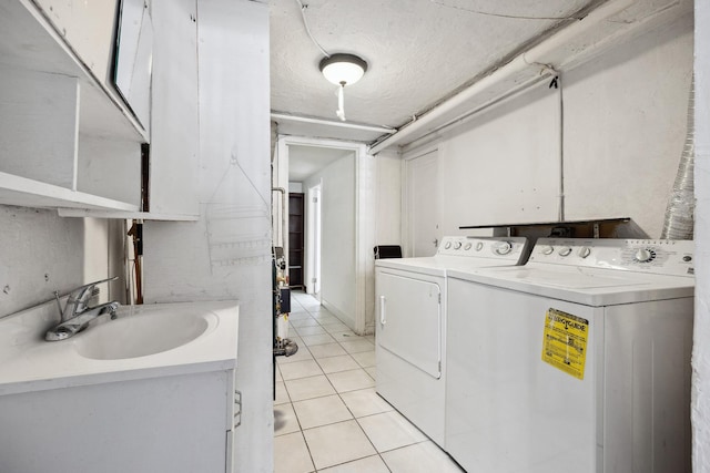 laundry room featuring light tile patterned floors, a sink, a textured ceiling, separate washer and dryer, and laundry area