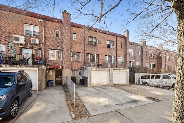 exterior space with driveway, a garage, and a wall mounted air conditioner