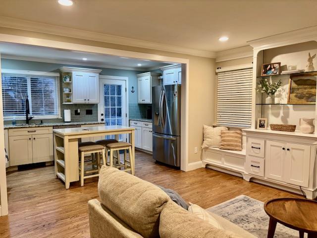 kitchen with wood finished floors, stainless steel fridge, a sink, and open shelves