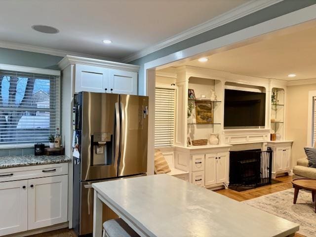 kitchen featuring ornamental molding, a fireplace with flush hearth, white cabinetry, and stainless steel fridge with ice dispenser