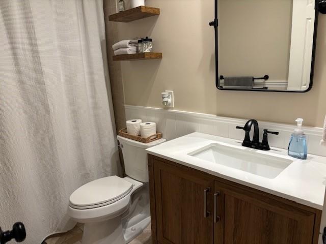 full bath with toilet, vanity, and wainscoting