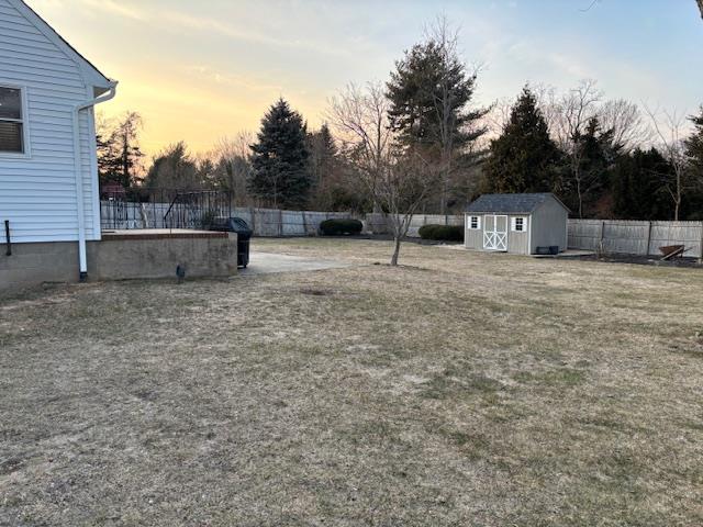 yard at dusk featuring a shed, fence, and an outdoor structure