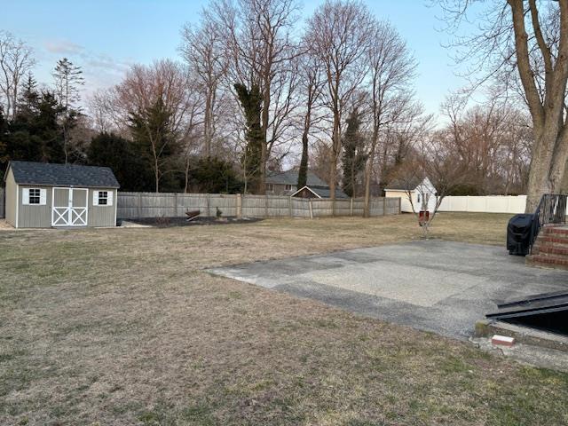 view of yard featuring an outbuilding, a storage unit, and a fenced backyard