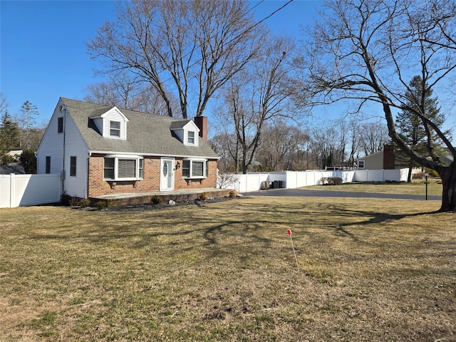 view of front of house with a chimney, brick siding, a fenced backyard, and a front lawn