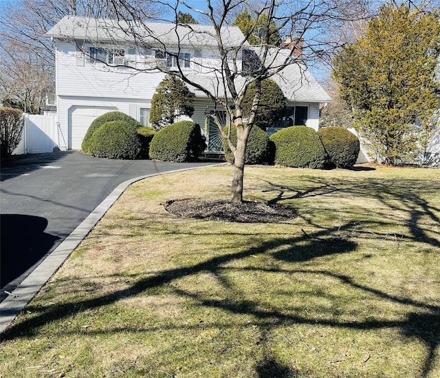 exterior space featuring aphalt driveway, fence, a garage, and a front yard