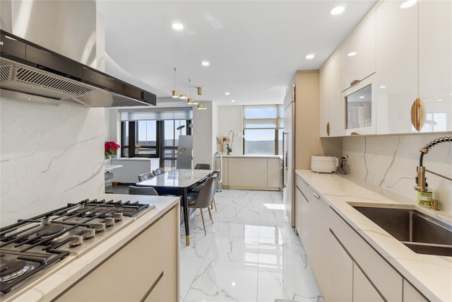 kitchen with light stone countertops, marble finish floor, stainless steel gas stovetop, a sink, and exhaust hood