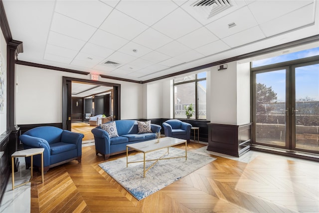 living room featuring a wainscoted wall, ornamental molding, a paneled ceiling, and visible vents