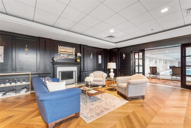 living room featuring ornamental molding, a fireplace, a decorative wall, and visible vents