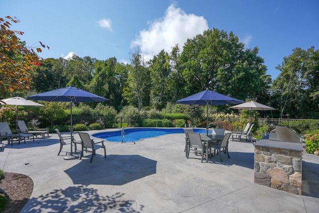 view of swimming pool featuring a patio area, fence, and exterior kitchen