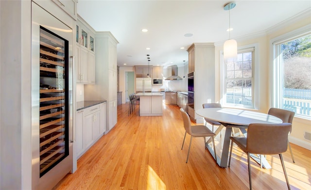 interior space featuring beverage cooler, ornamental molding, recessed lighting, and light wood-style floors