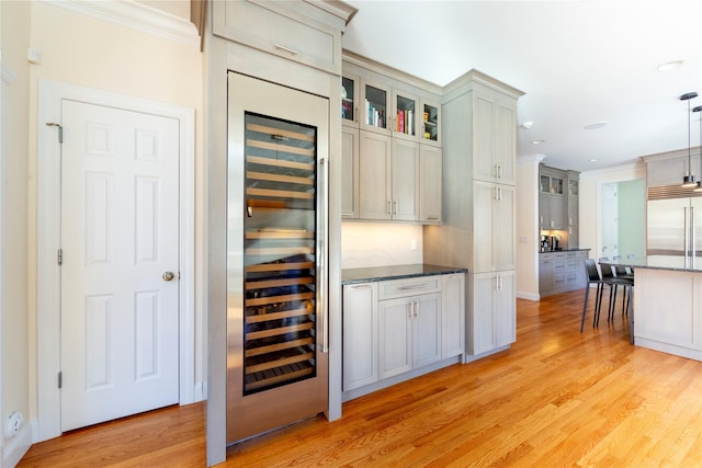 interior space with light wood-style flooring, glass insert cabinets, ornamental molding, stainless steel built in fridge, and beverage cooler