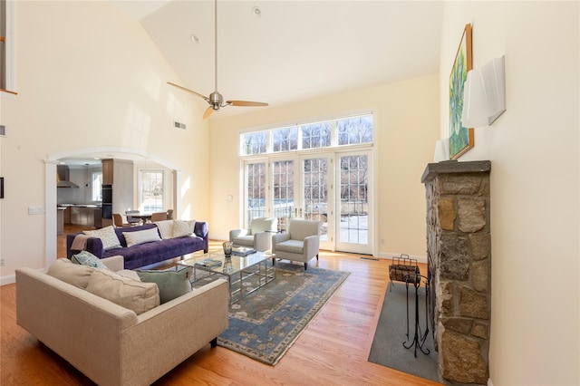 living room with arched walkways, visible vents, a ceiling fan, wood finished floors, and high vaulted ceiling