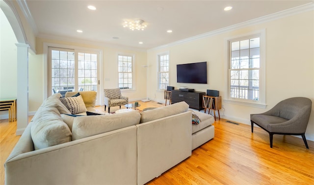 living area with visible vents, ornamental molding, a wealth of natural light, and light wood-style floors