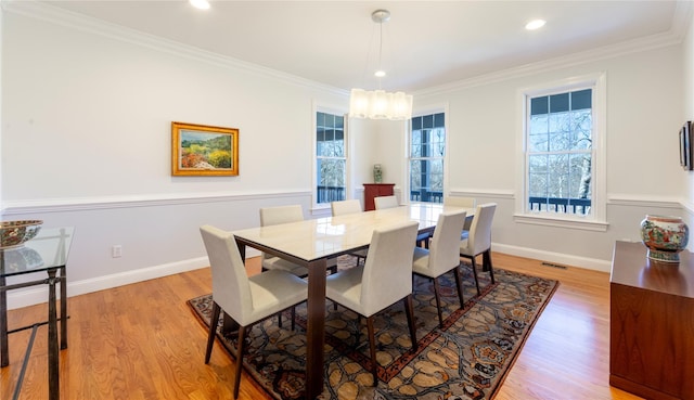 dining room with light wood-style floors, crown molding, and baseboards