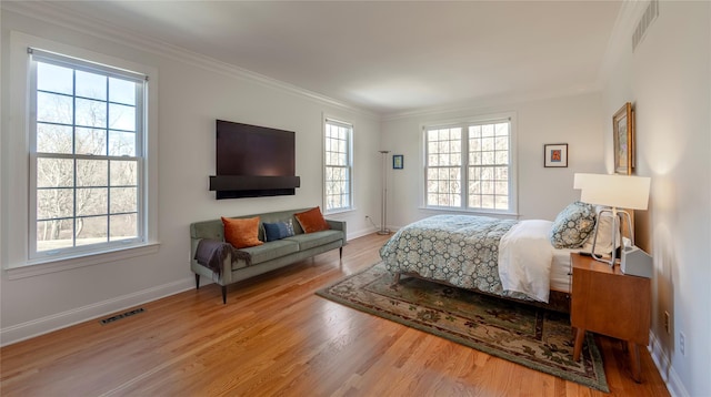 bedroom featuring ornamental molding, visible vents, baseboards, and wood finished floors