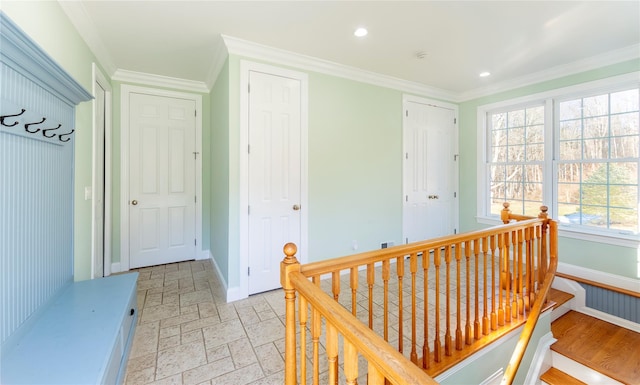 corridor with recessed lighting, stone tile floors, an upstairs landing, baseboards, and ornamental molding