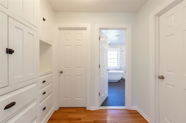 corridor with baseboards and light wood finished floors