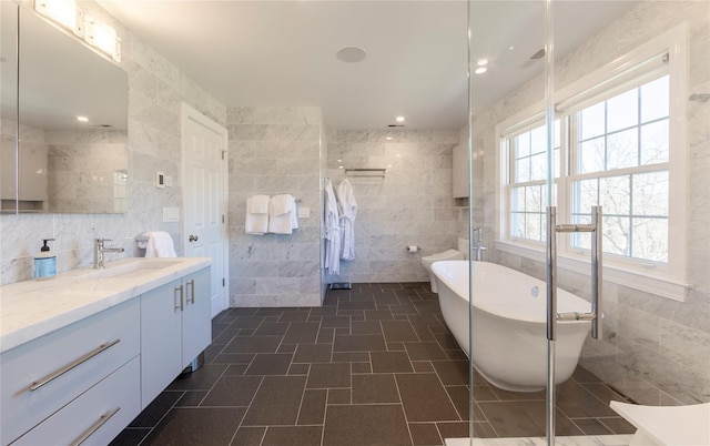 full bathroom with a freestanding bath, tiled shower, tile walls, and vanity