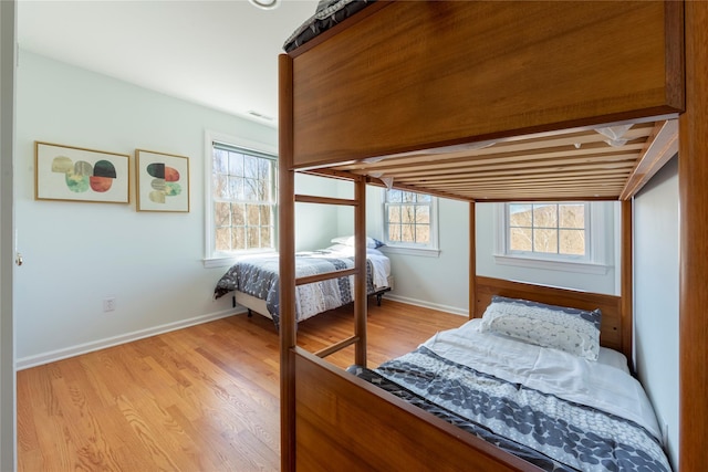 bedroom with light wood finished floors, visible vents, and baseboards