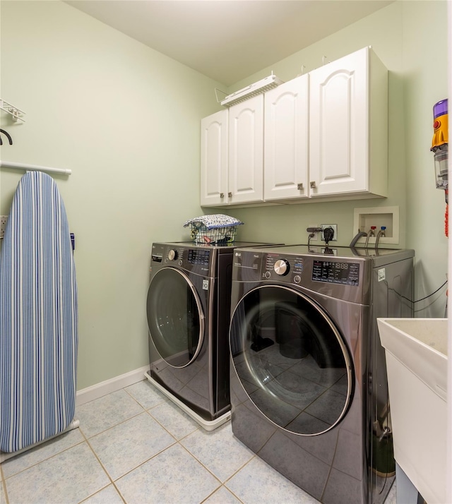 laundry area with cabinet space, light tile patterned floors, baseboards, independent washer and dryer, and a sink