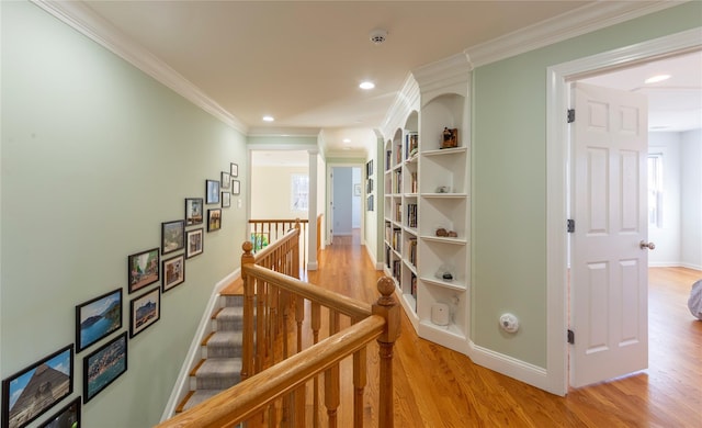 corridor featuring baseboards, ornamental molding, an upstairs landing, light wood-style floors, and recessed lighting