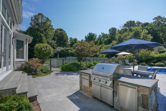 view of patio with exterior kitchen, area for grilling, fence, and a fenced in pool