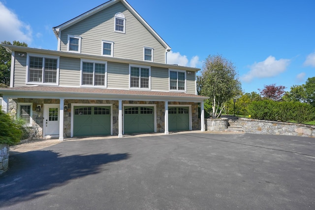 exterior space with a garage, stone siding, and aphalt driveway