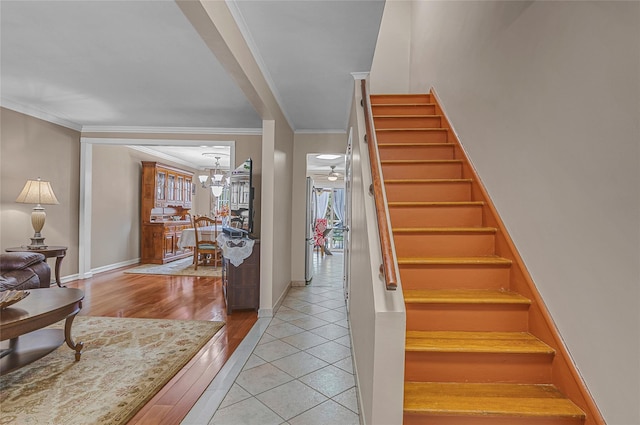 stairs featuring a notable chandelier, baseboards, crown molding, and tile patterned floors