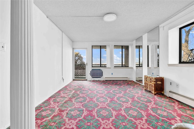 interior space with a baseboard heating unit, a textured ceiling, and a wall mounted air conditioner