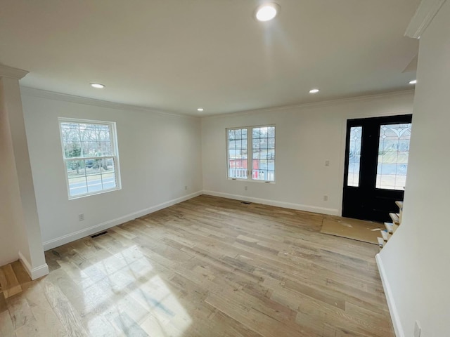 interior space featuring light wood-style floors, visible vents, ornamental molding, and baseboards