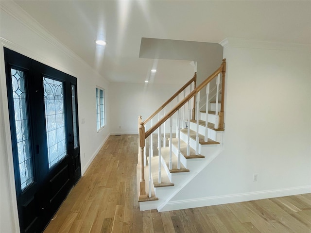 foyer entrance with stairs, crown molding, wood finished floors, and baseboards