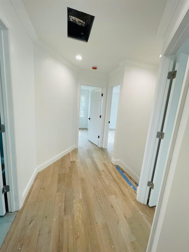 hallway with light wood-style floors, baseboards, ornamental molding, and recessed lighting