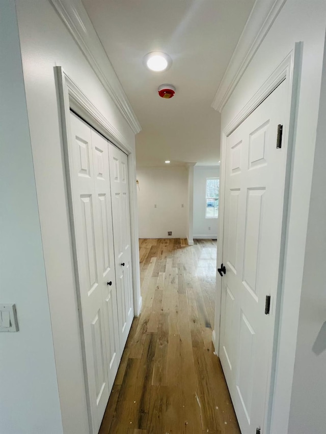 hallway with ornamental molding, baseboards, and wood finished floors