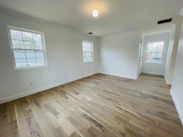 empty room featuring light wood-style floors, baseboards, and ornamental molding