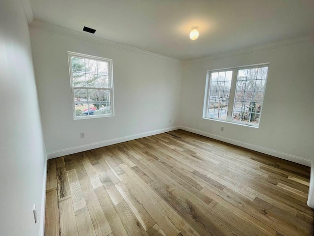 spare room with plenty of natural light, ornamental molding, and wood finished floors