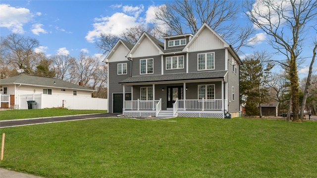 view of front facade with fence, a porch, a front lawn, aphalt driveway, and board and batten siding