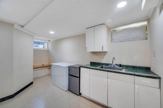 kitchen with recessed lighting, a sink, baseboards, white cabinets, and freestanding refrigerator