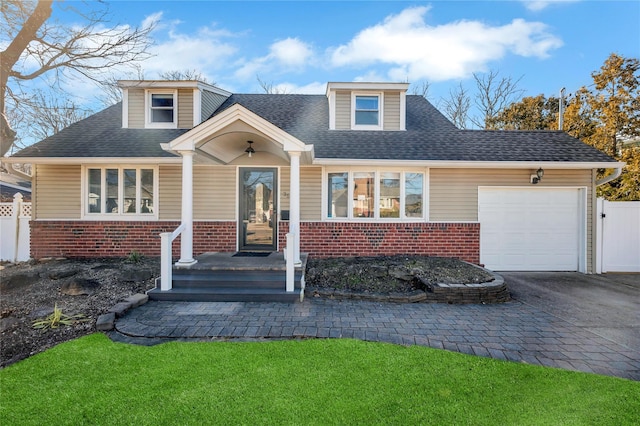 view of front facade with driveway, a shingled roof, fence, and brick siding