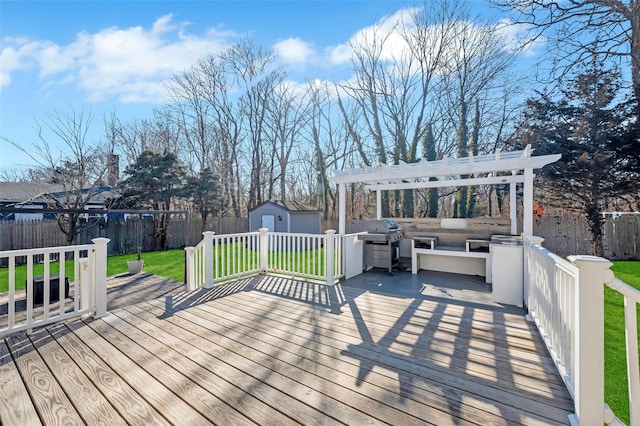 deck with a storage shed, a fenced backyard, a lawn, and an outbuilding