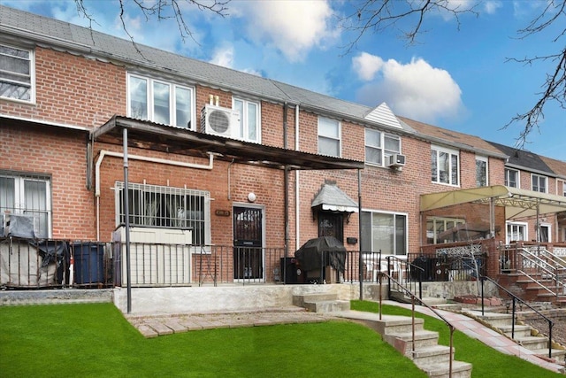 rear view of house featuring cooling unit, brick siding, and a yard