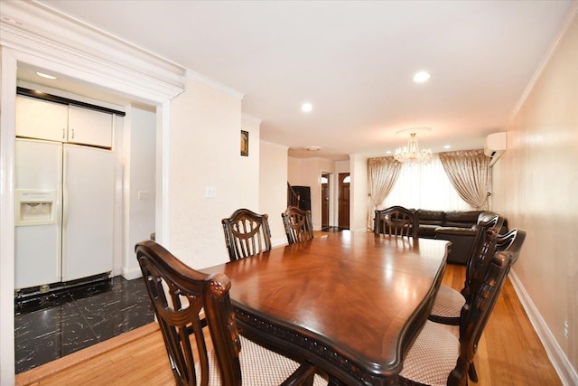 dining room featuring wood finished floors, baseboards, a wall mounted air conditioner, crown molding, and a chandelier