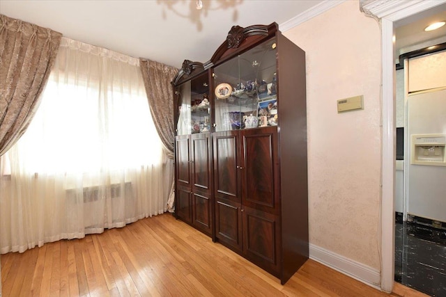 bar featuring baseboards, light wood-style floors, and crown molding