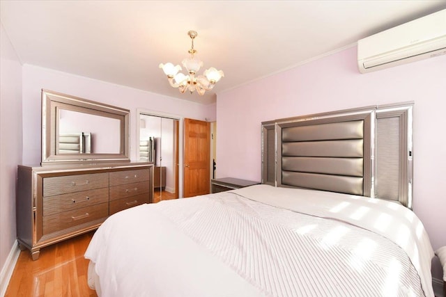 bedroom featuring light wood-style flooring, ornamental molding, a wall unit AC, a closet, and an inviting chandelier