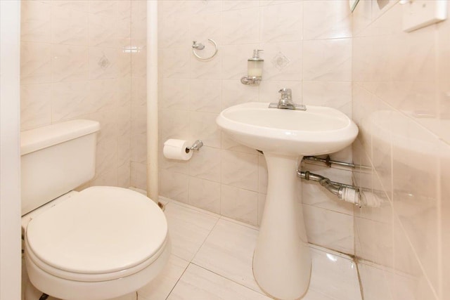 bathroom with tile patterned floors, toilet, and tile walls