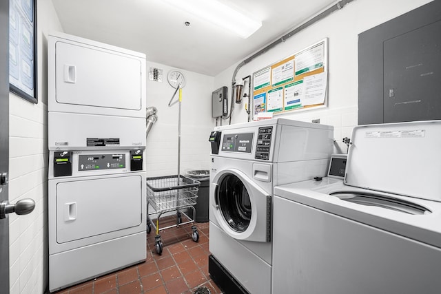 shared laundry area featuring dark tile patterned floors, electric panel, separate washer and dryer, and stacked washer / dryer