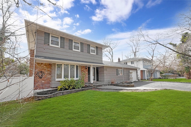 view of front of house with aphalt driveway, a front yard, brick siding, and an attached garage