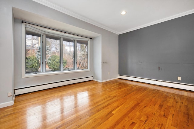 spare room with a baseboard radiator, ornamental molding, and wood finished floors