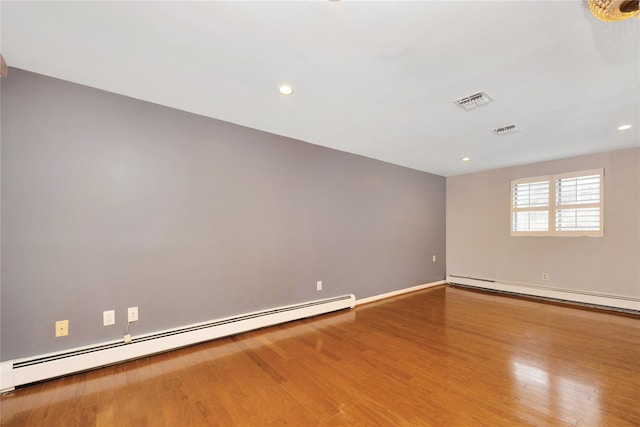 spare room featuring a baseboard radiator, visible vents, baseboard heating, and wood finished floors