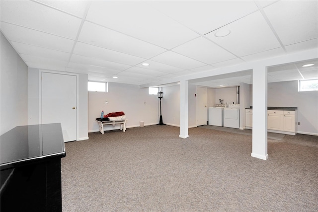 below grade area with carpet flooring, independent washer and dryer, a drop ceiling, and baseboards